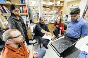 Aseem Ansari talks with his research group