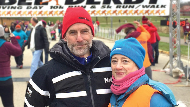 Man and woman standing outside at race dressed for cold weather hats and jackets