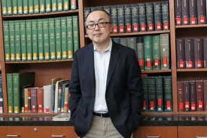 Glen Kwon standing in front of shelves of books