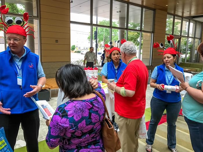 A group of people with crab hats talk to other people