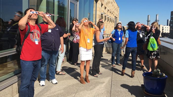 Group of IPSEC participants outside looking through eclipse glasses