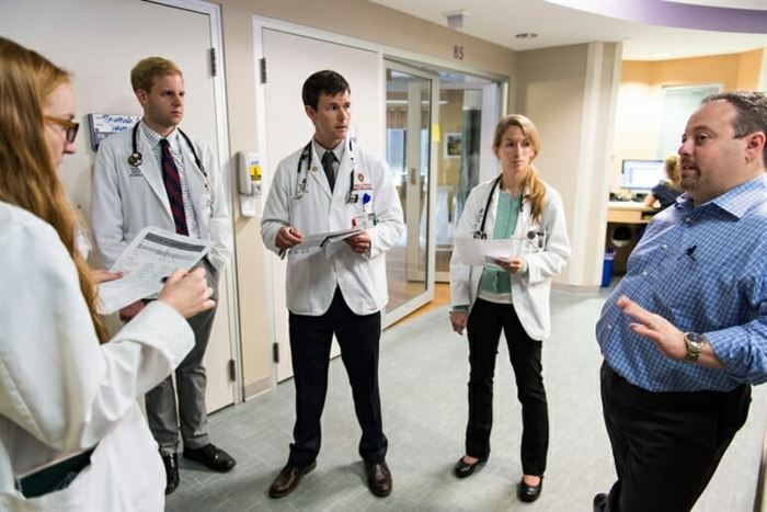 Joshua Medow standing meeting with staff at a UW hospital