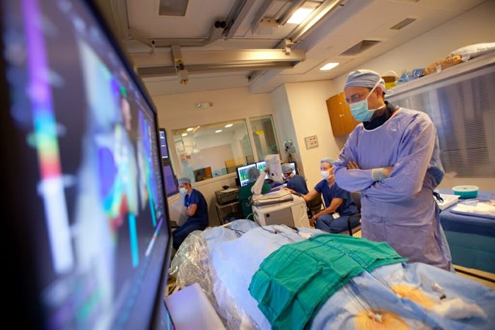 Doctor in scrubs looks down at a covered patient