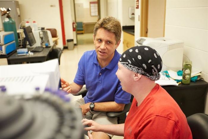 Rob McGaff and Megan Timmers talking in a small office or lab space