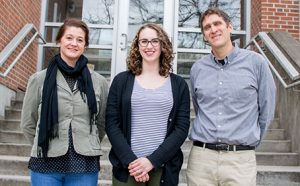 Katie Gold, Amanda Gevens & Phil Townsend standing in front of steps leading to a brick building