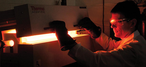 Mike Arnold peers into an oven used to fabricate sheets of semiconducting graphene