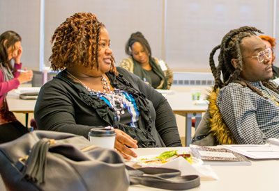 People sitting at table listening to a speaker