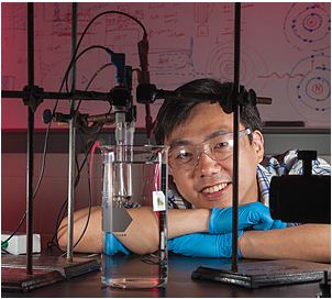 Xudong Wang resting head on arms behind a beaker set